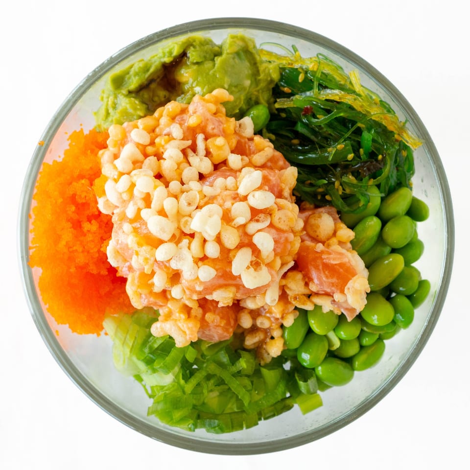 Top-down view of a POKÉ + GO poke bowl with salmon, avocado, seaweed, edamame, and roe.