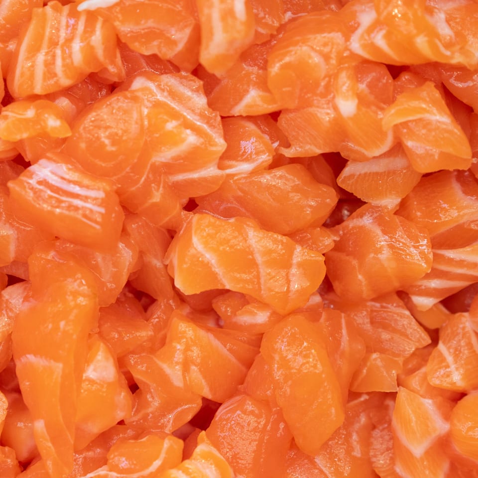 Close-up of fresh, diced orange salmon pieces, ready for a POKÉ + GO poke bowl.