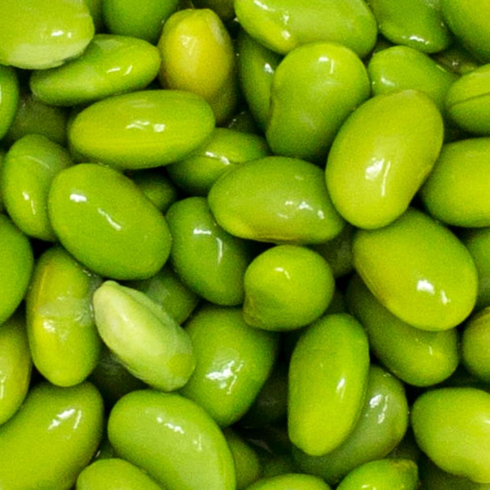 Close-up of bright green edamame beans, some with a slight sheen, filling the frame.